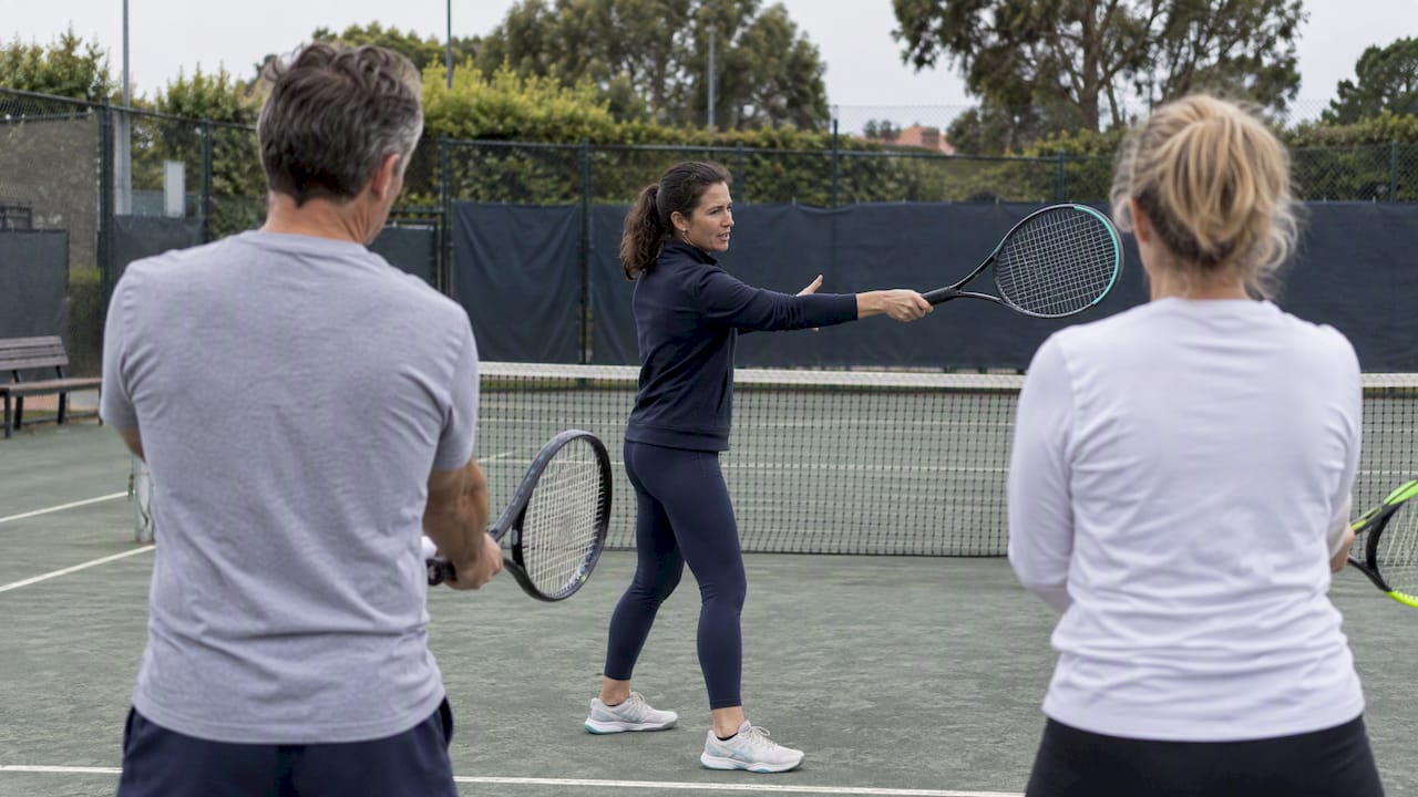 Allenatore che insegna ai principianti su un campo da tennis