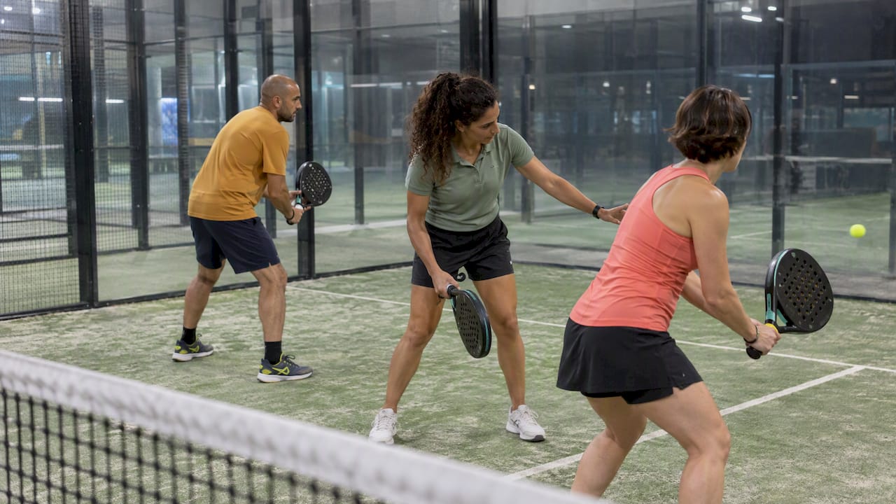 L’insegnante segue due allievi durante una lezione di padel